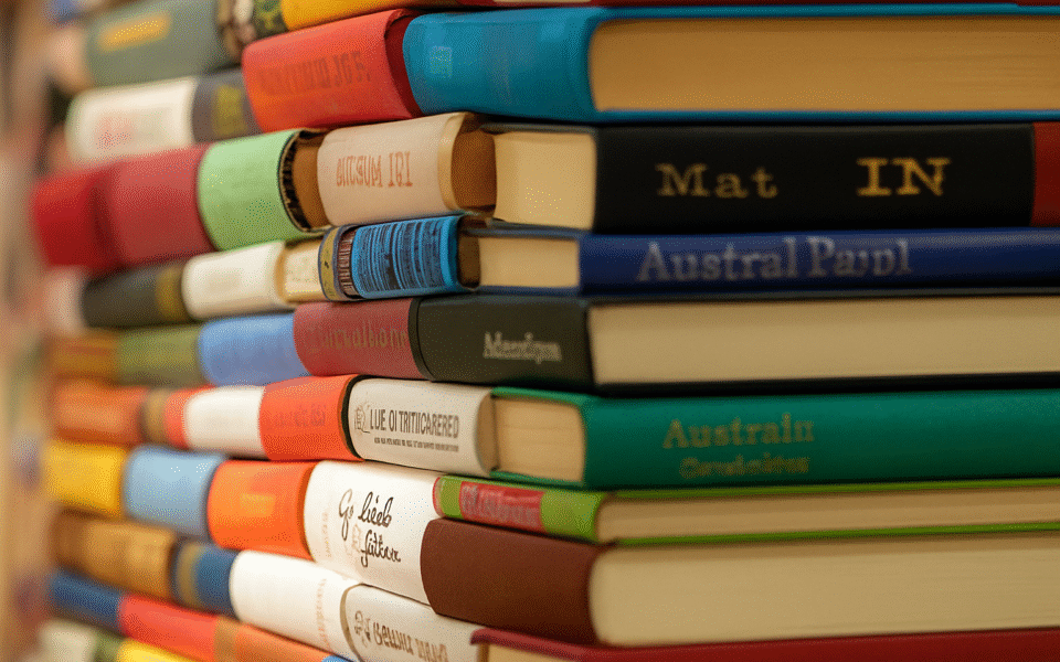 Zdjęcie przedstawia kolorowy, ciasno ułożony stos książek, widoczny z perspektywy grzbietów.